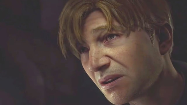 A white man with straw-blonde hair is looking upwards with a look of pain on his face.